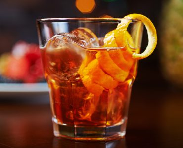 Receitas harmonização com uísque whisky glass of delicious alcoholic cocktails or lemonade with ice, decoration of fresh berries on a wooden table in a bar or restaurant with a beautiful bokeh in the background. soft focus.