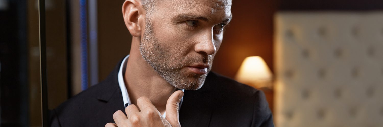 Club Model Estilos de Barba para Rosto Oval Redondo Quadrado Triangular Diamante Homem Queixo Handsome Man In Fashion Clothes In Luxury Interior. Closeup Portrait Of Successful Wealthy Confident Business Man In Stylish Elegant Suit, Expensive Watch In Fashionable Luxurious Apartment. Wealth